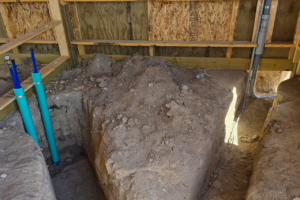 Underground horse barn plumbing and water line trenching inside a custom post frame horse barn in Castle Rock Colorado before concrete installation.